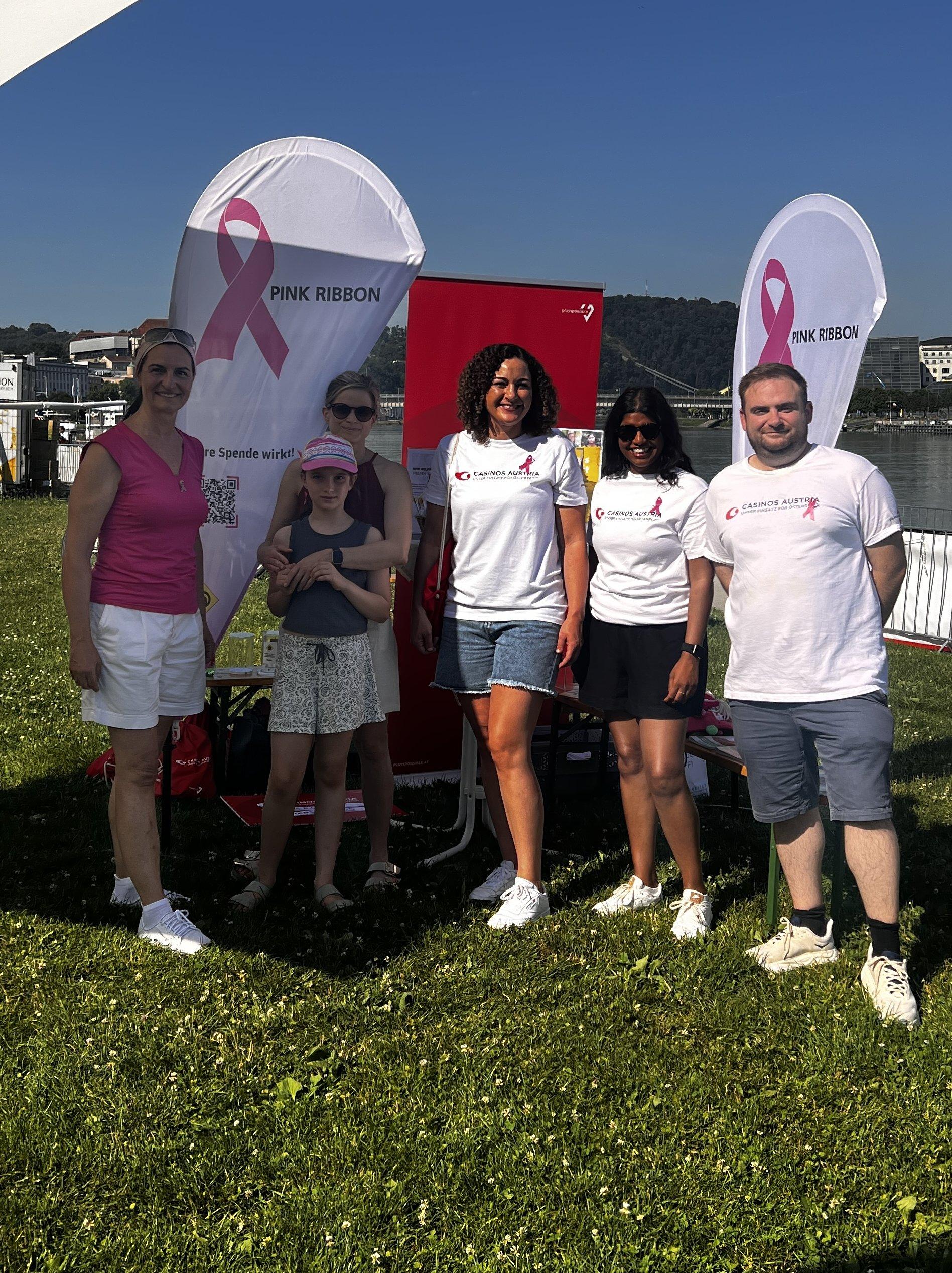 Das Team der Krebshilfe OÖ und des Casinos Linz posieren vor Pink Ribbon und Casinos Flyer.