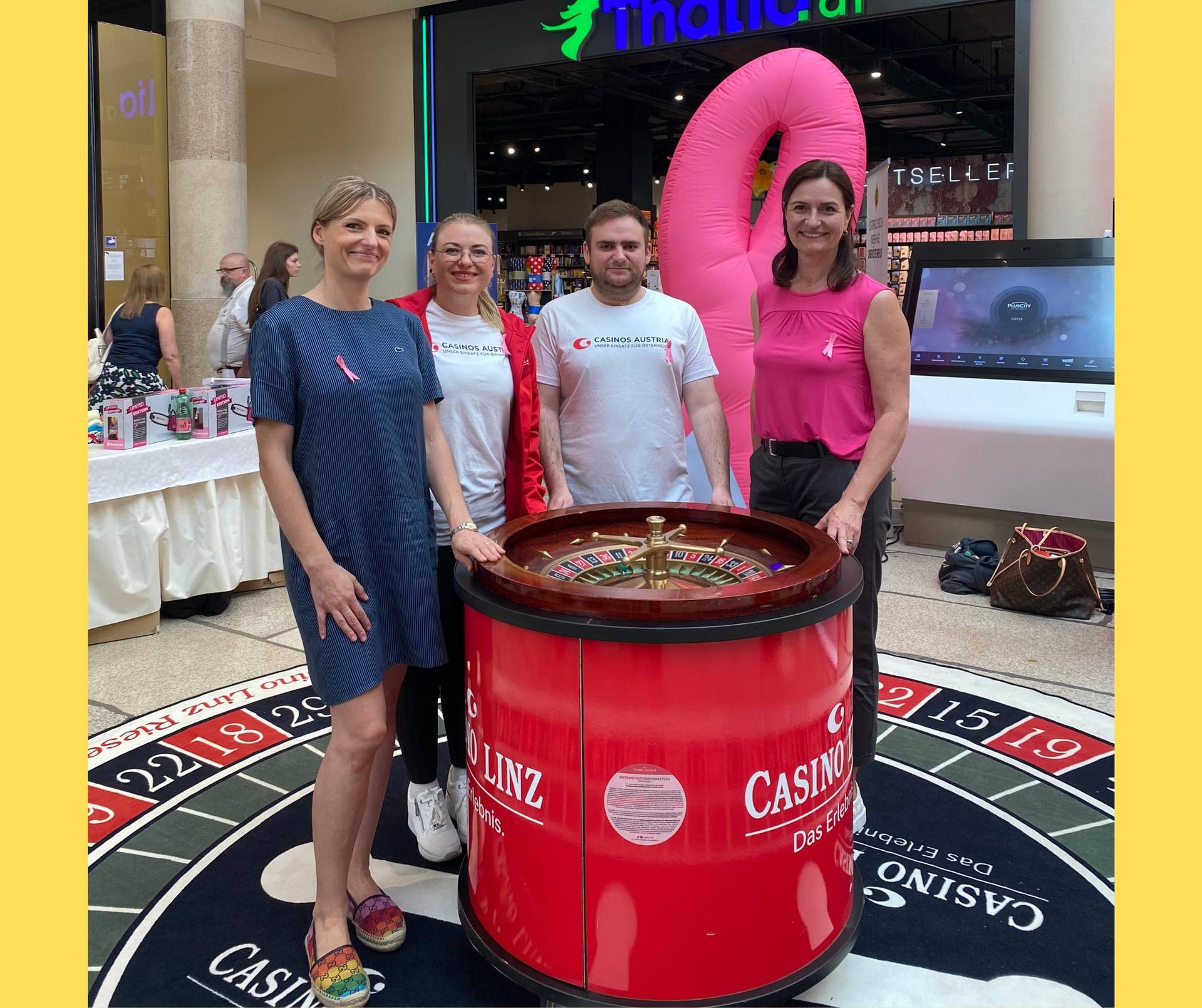 Maria Sauer mit Mitarbeiterinnen und Mitarbeiter vom Casinos Austria. Vor ihnen ist ein Roulette Tisch.
