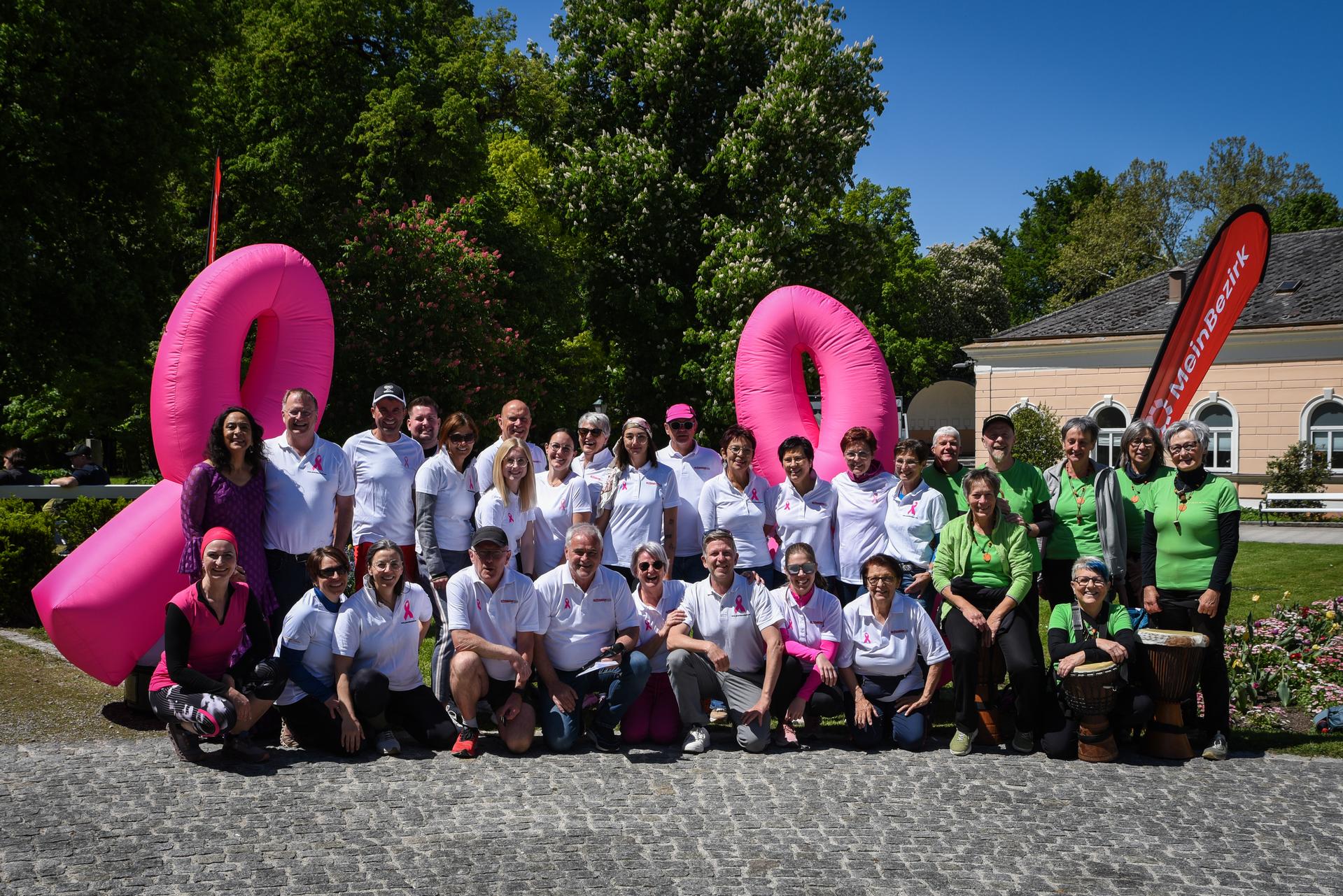 Ein Gruppenfoto einer Läufergruppe vor zwei aufblasbaren Pink Ribbon Schleifen