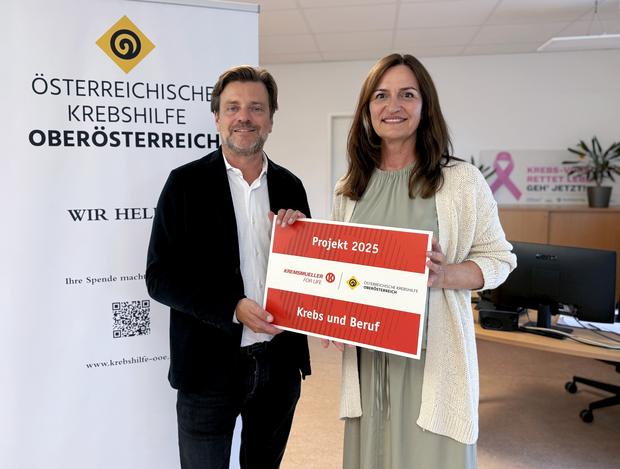 Gregor Kremsmüller übergibt Maria Sauer eine symbolische Plakette mit der Aufschrift "Projekt 2025 - Krebs und Beruf"