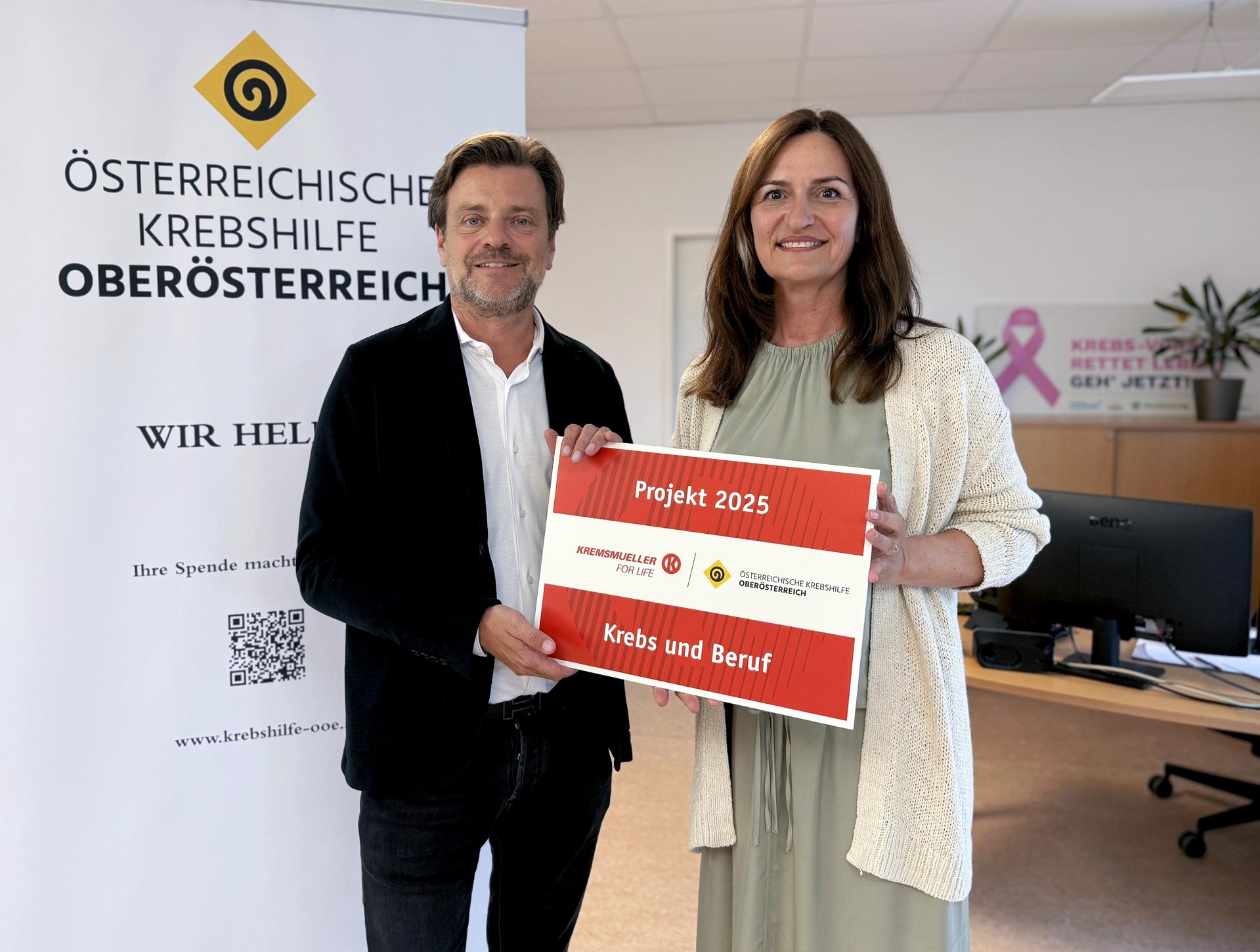 Gregor Kremsm&uuml;ller &uuml;bergibt Maria Sauer eine symbolische Plakette mit der Aufschrift "Projekt 2025 - Krebs und Beruf"