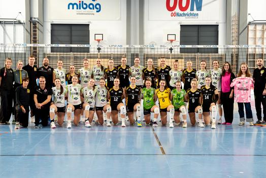 Die Spielerinnen der LINZ AG Steelvolleys und des UVC Holding Graz und das Trainerteam posieren in verschiedenen Trikots vor einem Volleyballnetz. Das Bild wurde während des Heimspiels am 18. Oktober 2025 aufgenommen, das im Zeichen der Frauengesundheit stand.