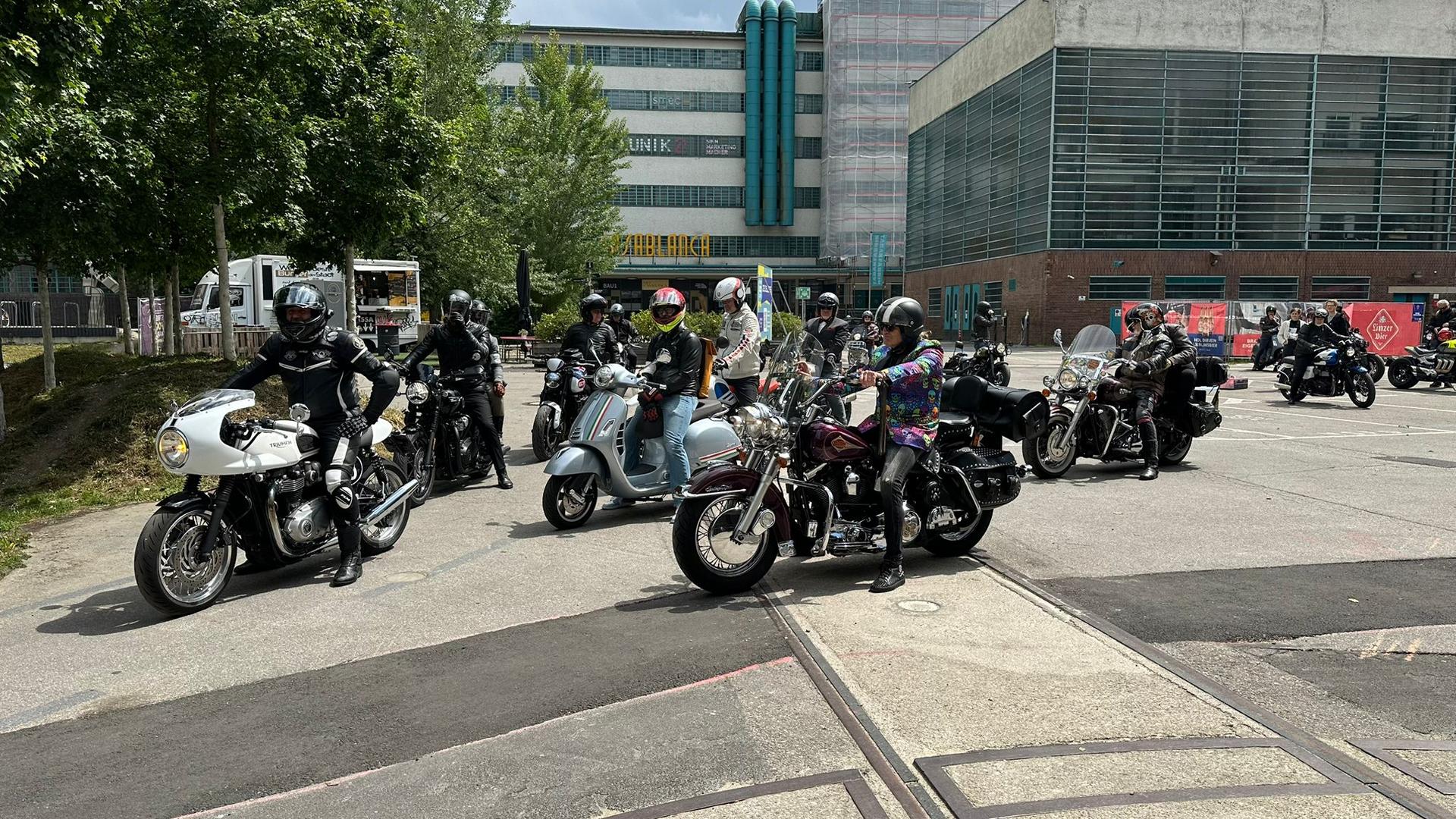 Mehrere laufende Motorräder mit den Fahrern darauf, die auf die Ausfahrt warten.