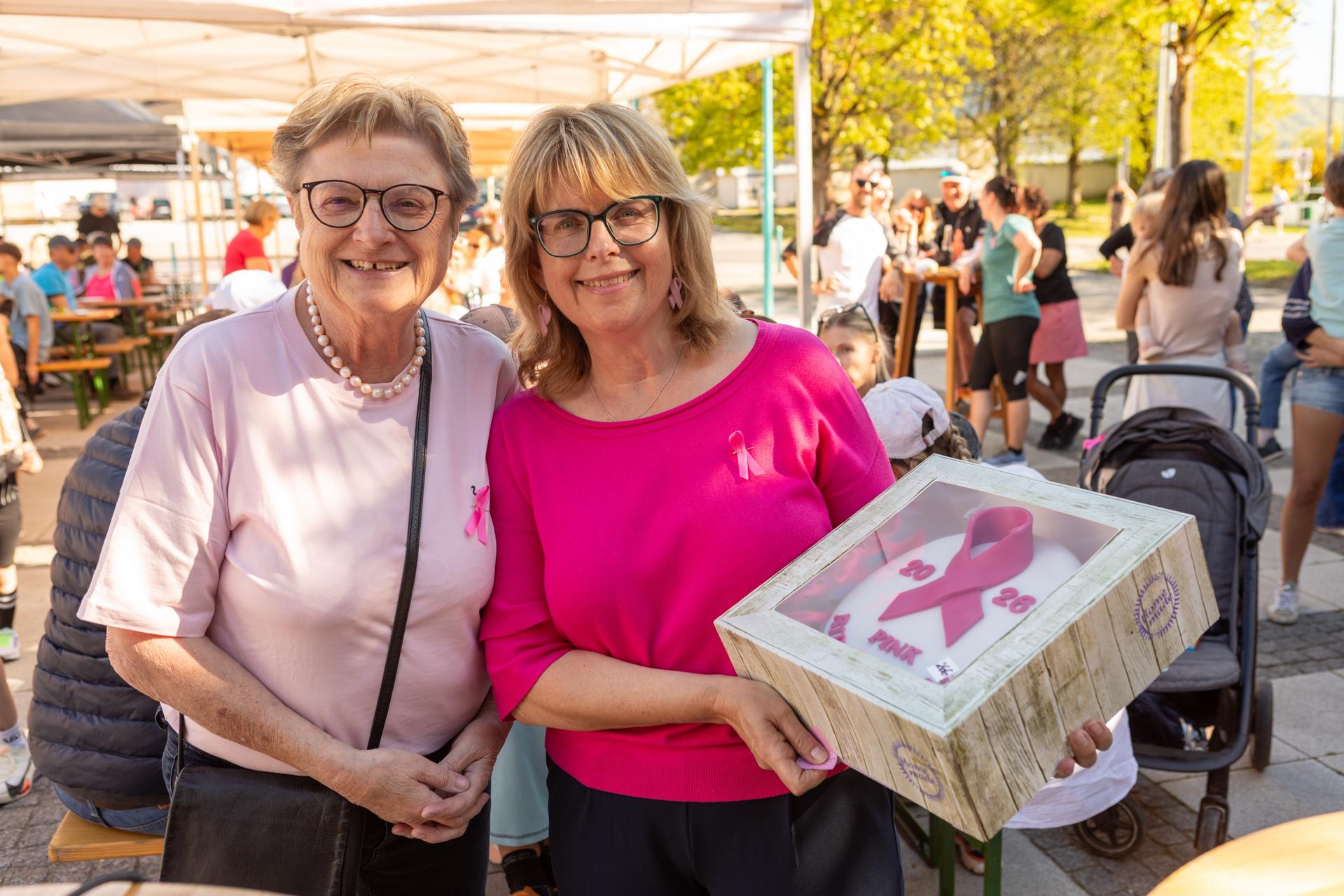 Veranstalterinnen des Pink Ribbon Days mit einer Torte, die mit dem Pink Ribbon verziert ist